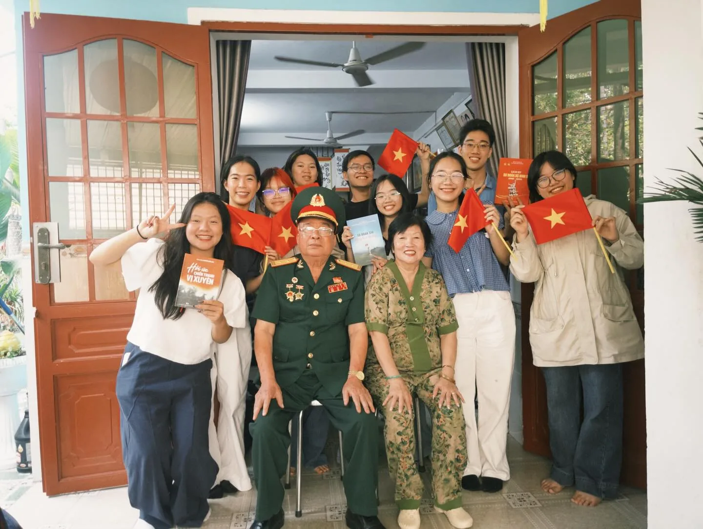 Các bạn trẻ chụp ảnh cùng một bác cựu chiến binh và gia đình tại nhà bác.